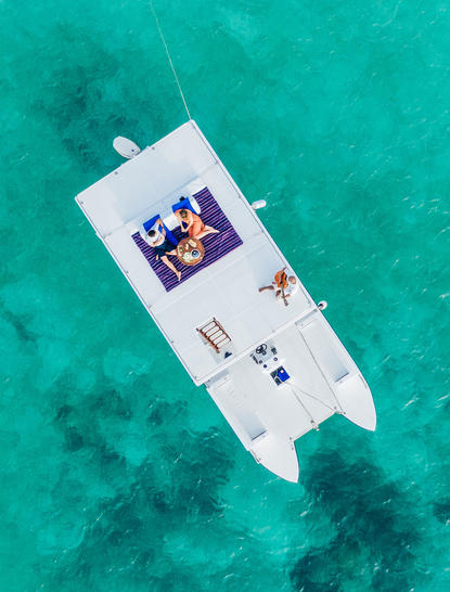 Aerial view of a white yacht moored in turquoise waters at Amanpulo resort.