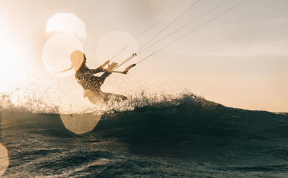 アマンプロのリゾートで、夕日を背景にウェイクボーディングを楽しむ人。