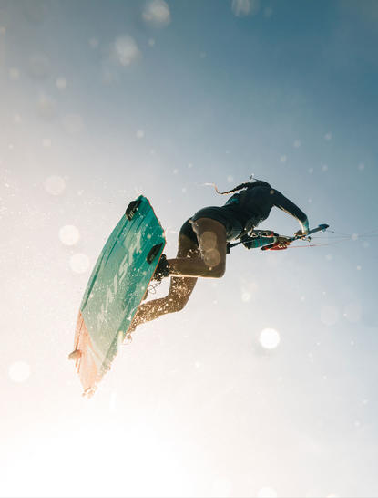 Surfer in mid-air with turquoise board at Amanpulo resort.
