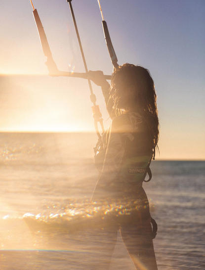 Surfer holding kiteboard at sunrise on Amanpulo resort beach, Philippines.