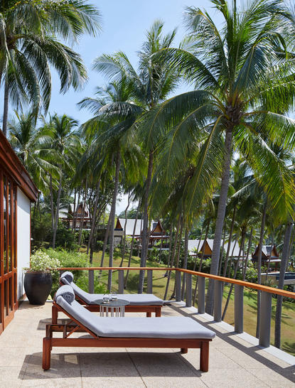 Eight-bedroom garden villa with wooden lounger on terrace overlooking tropical gardens at Amanpuri.