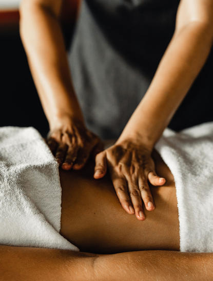 Therapist's hands performing a massage treatment on a guest's back at Amanpuri resort.