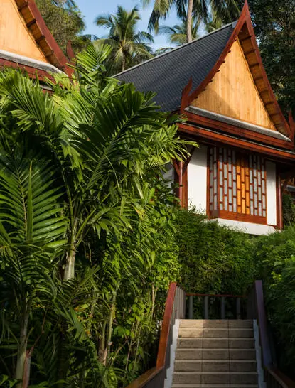 Pavilion de jardin aux toits traditionnels thaïlandais et volets dorés, entouré de palmiers à Amanpuri.