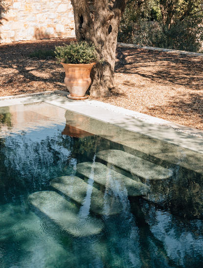 Pool pavilion with partial sea view at Amanruya, featuring stone seating beside clear turquoise water.