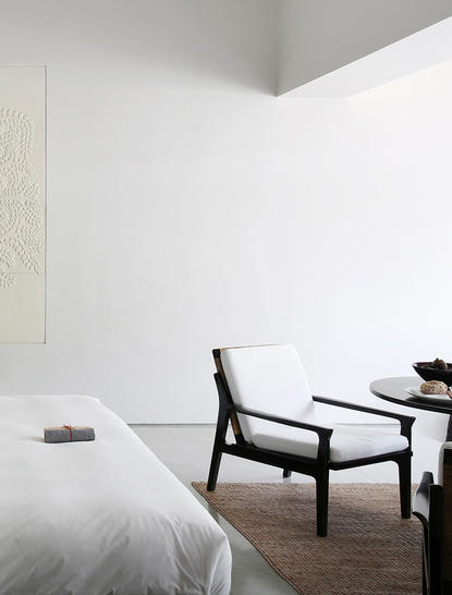 Courtyard Suite bedroom at Amansara with minimalist white walls, wooden flooring, and modern furnishings.
