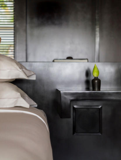 Principal bedroom with dark stone bathtub at Amansara, view towards window and bedside table.