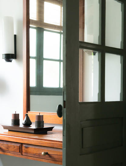 Pool Suite bathroom at Amantaka with wooden vanity and dark green door.