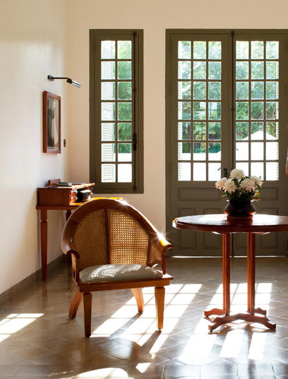 Pool Suite at Amantaka with wooden chair beside tall glazed doors opening to gardens.