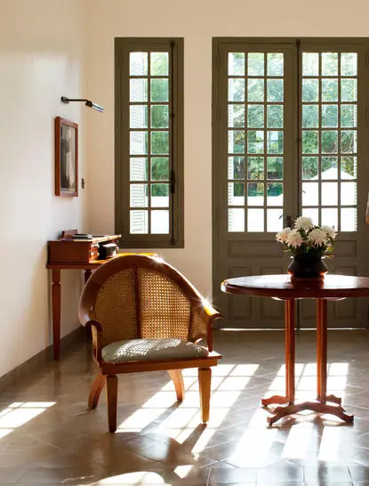 Pool Suite at Amantaka with wooden chair beside tall glazed doors opening to gardens.