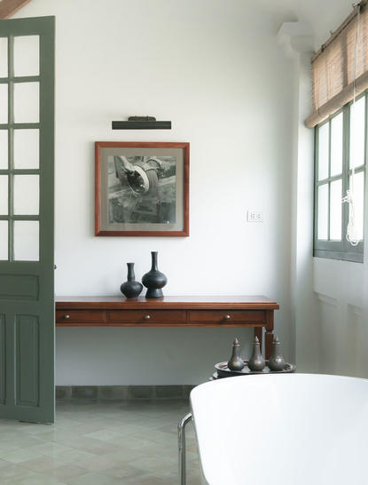 Principal bedroom bath at Amantaka with freestanding tub, wooden console and framed artwork.