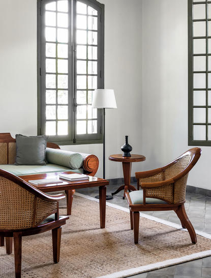 Mekong Pool Suite sitting area at Amantaka with wooden chairs and desk beside tall windows.