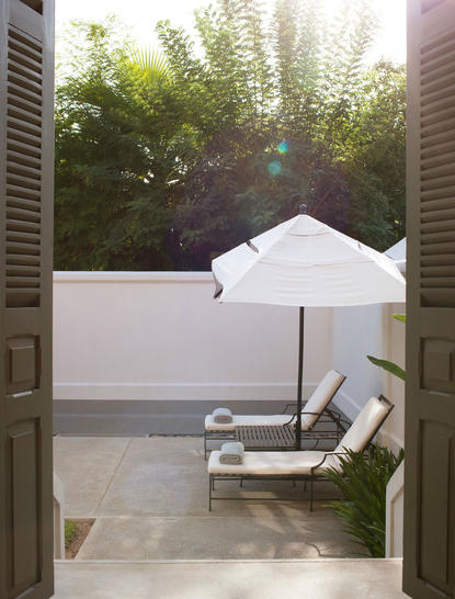 Pool Suite at Amantaka with sunlit garden view and lounge chair on terrace.