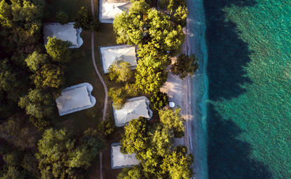 安缦湾澜度假村鸟瞰图，展示海滨帐篷、沙滩和绿松石色海水。