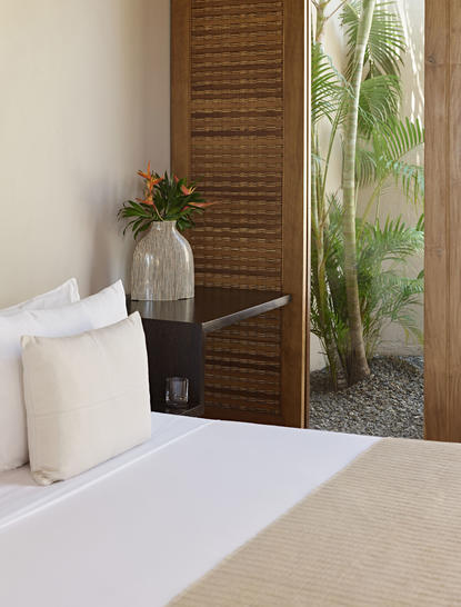 Garden Pool Suite bedroom at Amanwella with wooden screen and potted plant beside bed.
