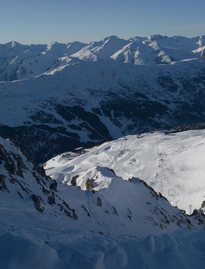 Chaîne montagneuse enneigée avec vallée glaciaire, vue depuis Aman Le Mélézin en station de montagne.
