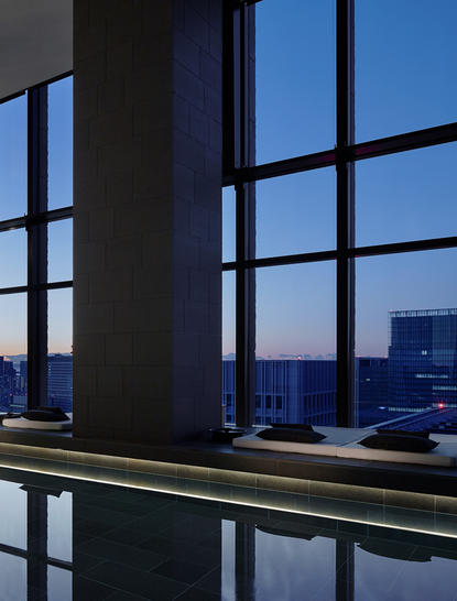 Corner Suite at Aman Tokyo with floor-to-ceiling windows overlooking the city skyline at dusk.