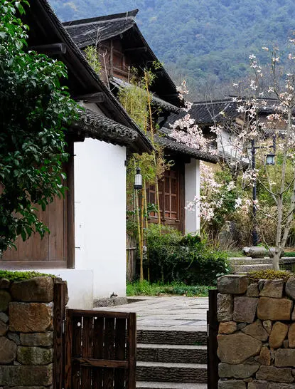 Deluxe Village Suite exterior at Amanfayun, with traditional architecture and verdant garden entrance, China.