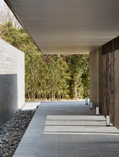 Covered walkway with stone flooring at Amanemu resort, Japan, with ivy-covered walls and natural light.
