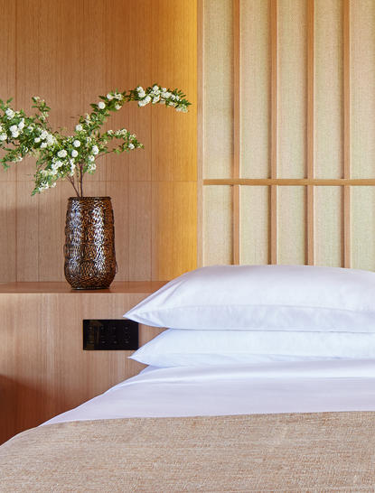 Principal bedroom with white pillows and wooden panelling at Amanemu resort, Japan.