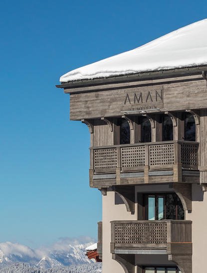 Aman Le Mélézin's architectural detail with snow-capped Alpine peaks visible beyond.