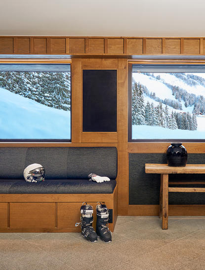 Ski suite at Aman Le Mélézin with wood-panelled walls, snow-capped mountain views, and an outdoor hot tub.
