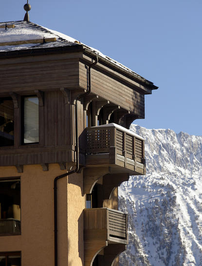 Exterior of a suite at Aman Le Mélézin resort with snow-capped Alpine peaks beyond.