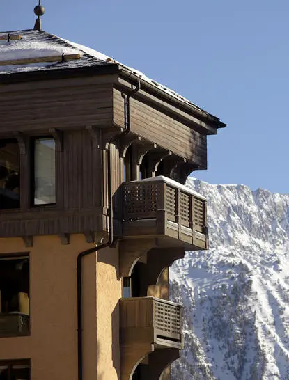 Façade d'Aman Le Mélézin avec vue sur les pistes enneigées, station de montagne française.