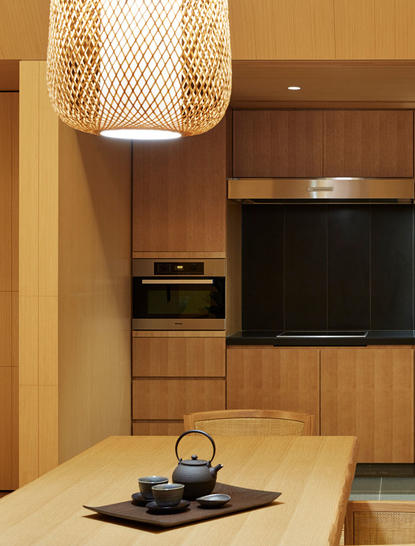 Cuisine de villa avec armoires en bois clair, plan de travail blanc et équipements intégrés à Amanemu, resort au Japon.