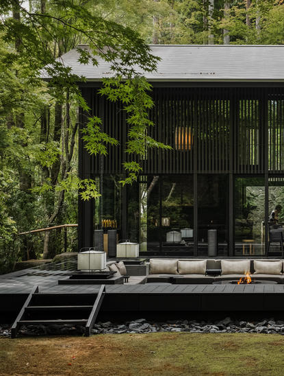 アマン京都のリゾートの木立に囲まれた、緑の壁に沿う現代的な黒い建築物