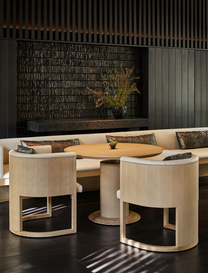 アマン京都のリビング・パビリオン内部。木製の曲線的なデスクと椅子、黒い壁面のアート作品。