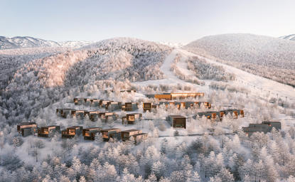 Aerial view of Aman Niseko retreat nestled among snow-covered forests in Japan's winter landscape.