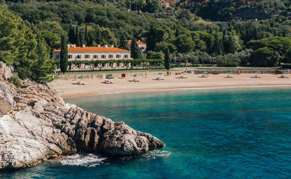 Aman Sveti Stefan's terracotta-roofed buildings perched on a rocky peninsula above turquoise Adriatic waters.