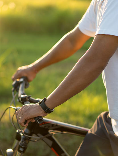Cyclist's hands on handlebars at Amandari, with green landscape in background.