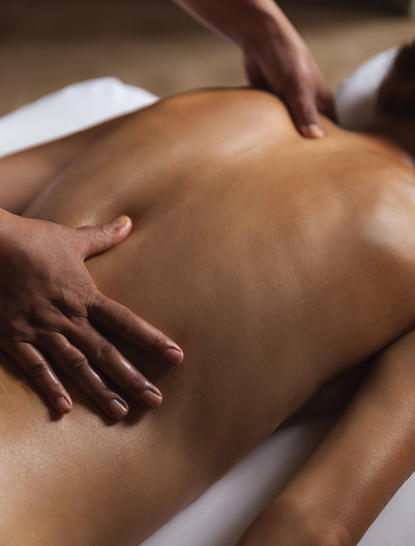 Therapist's hands performing a massage on a guest's back at Amanjiwo wellness retreat.