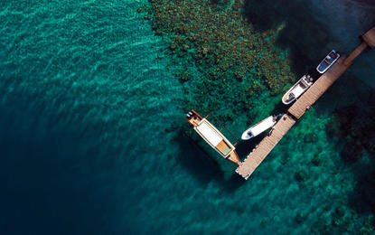 Aerial view of the dive centre at Amanwana with boats moored in clear turquoise waters.