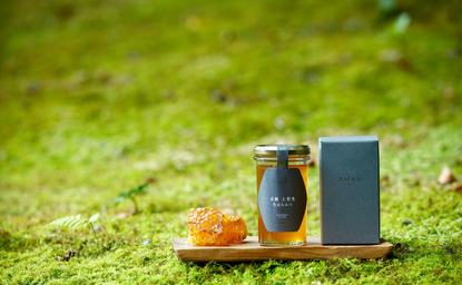 アマン京都のリゾートに飾られた蜂蜜の瓶と木製の容器が苔の上に置かれている。