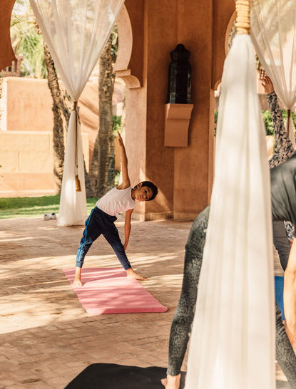 Famille pratiquant le yoga ensemble dans une cour couverte à Amanjena.