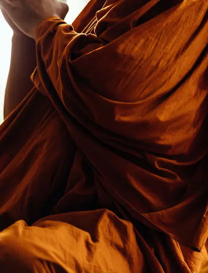 Warm sunlight illuminates flowing rust-coloured fabric during a mindfulness session at Amanpuri.