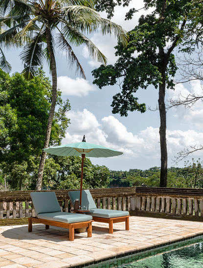 Ayung Suite at Amandari resort with wooden deck, loungers, and valley views framed by palm trees.
