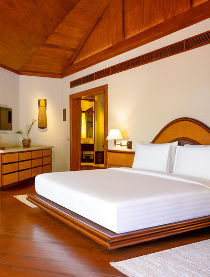 アマンプロのリゾートに位置するビーチカシータの広々とした主寝室。木製の天井と温かみのある照明が特徴。