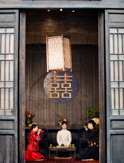 Three people seated at a wooden table beneath a traditional Chinese doorway at Amanfayun.