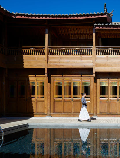Spa attendant in white uniform seated by the swimming pool at Amandayan, China.