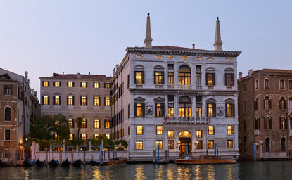 Palazzo illuminated at dusk along the Grand Canal at Aman Venice, with traditional Venetian architecture reflected in the water.