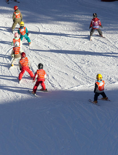 Enfants skiant sur les pentes enneigées d'Aman Le Mélézin, une station de montagne.