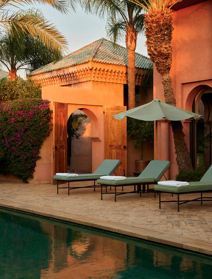 Al Hamra Maison at Amanjena with terracotta walls, loungers by the pool, and palm trees.