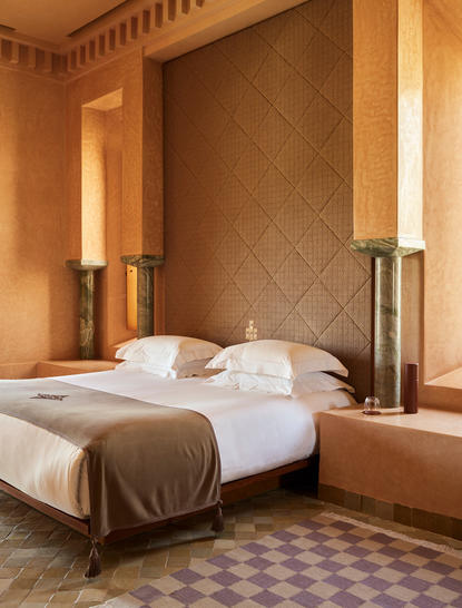 Maison bedroom with double bed and warm terracotta walls at Amanjena resort.