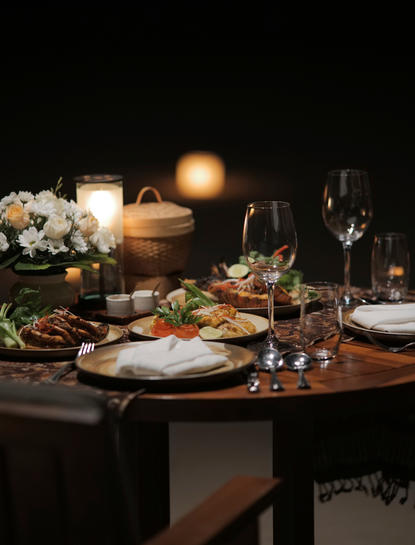 Candlelit dining table set for dinner at Aman Villas at Nusa Dua, with flowers, glasses, and place settings.