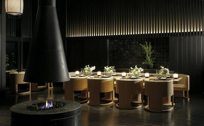 安缦京都度假村的餐厅，木质长餐桌周围置有多把椅子，柔和灯光照亮简约用餐空间。