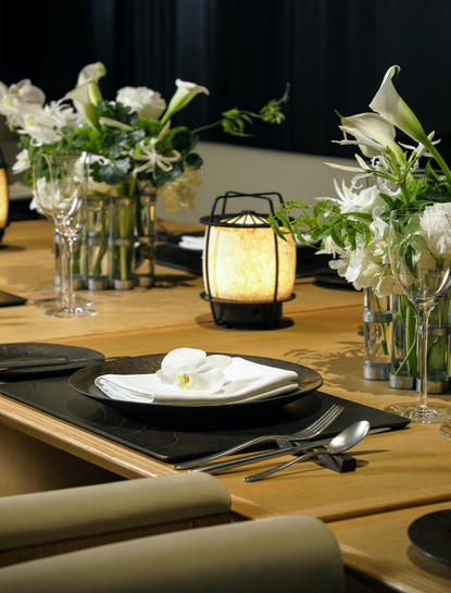 安缦京都度假村的餐桌布置，玻璃花瓶中插着白色鲜花，黄色灯笼和黑色餐具