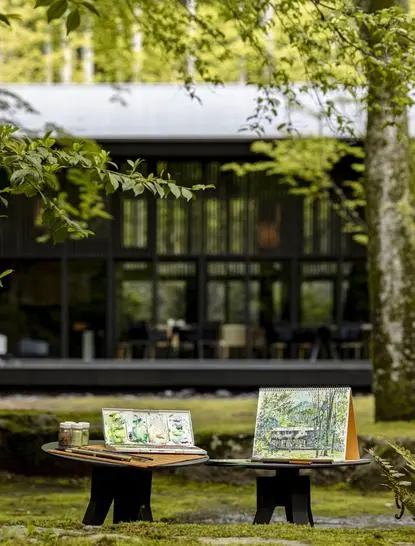 Wooden bench beneath trees overlooking manicured gardens at Aman Kyoto resort.
